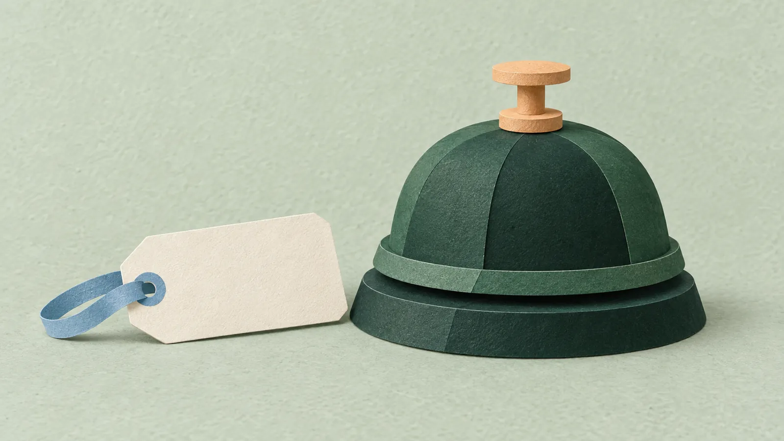 Forest-green paper reception bell with an apricot top beside a blank ivory luggage tag on sage paper.