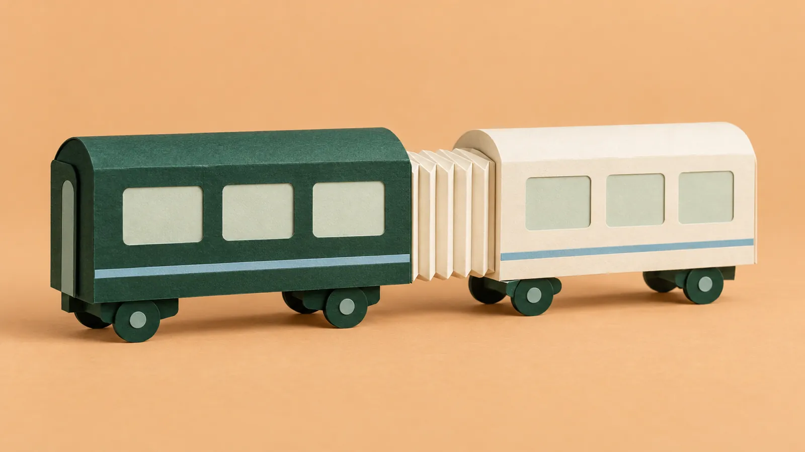 Green and ivory paper train carriages join through an accordion-fold connector on an apricot background.