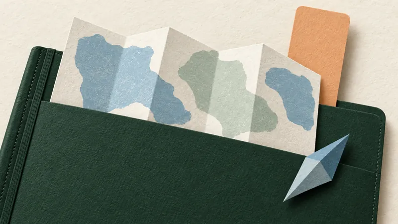 Paper-cut folded map in a green notebook pocket with an apricot bookmark and a blue compass needle.